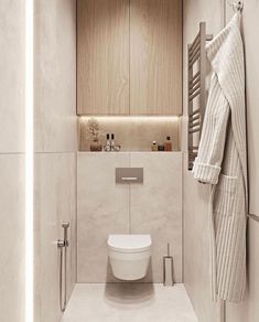 a white toilet sitting in a bathroom next to a towel rack and wooden cabinet above it