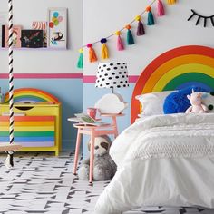 a child's bedroom decorated in bright colors with rainbow accents and decor on the walls