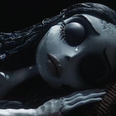 a creepy doll is laying down with her eyes closed