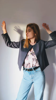 a woman standing in front of a white wall with her arms stretched out and hands behind her head