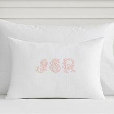 the embroidered monogrammed pillow is shown on a white bed with pink trimmings