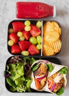 two trays filled with different types of food including fruit, chips and veggies