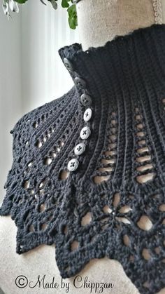 a black crocheted shawl with buttons on it