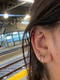 a woman with ear piercings standing next to a train