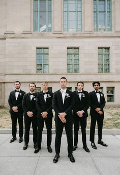 a group of men standing next to each other in front of a building