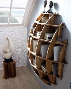 a wooden shelf with many books on top of it next to a white vase and window