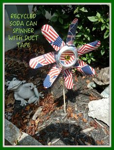 a metal pinwheel with american flags on it and a frog sitting in the background