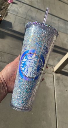 a hand holding a glitter starbucks cup with a straw sticking out of the top and lid