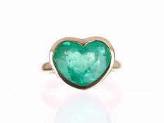 This ring is not for the faint of heart! Displayed is a large Colombian emerald heart solitaire ring in 14K gold. This gorgeous solitaire ring is bezel set in yellow gold and carries a full 6.10-carat emerald that will have you gazing at its mystic beauty. This large gem has minor imperfections as no natural emerald is flawless. This emerald is absolutely stunning and will have you captivated at first glance. This ring is one of a kind and made by our company in South Florida, USA. Setting Style Formal Heart Cut Emerald Ring, Fine Jewelry Heart Ring With Bezel Setting, Fine Jewelry Heart Cut Ring With Bezel Setting, Heart Cut Bezel Set Heart Ring, Heart-shaped Emerald Ring For Anniversary, Heart Cut Emerald Ring For Anniversary, Heart Cut Rings With Bezel Setting, Heart Solitaire Ring, Emerald Gold Ring