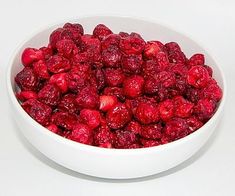 a white bowl filled with raspberries on top of a table