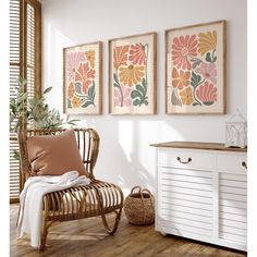 three framed art prints hang on the wall above a chair and sideboard in a white room