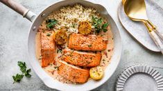 salmon and rice in a skillet with lemons, parsley on the side