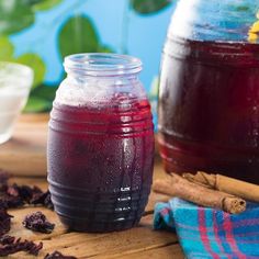 two jars filled with liquid sitting on top of a wooden table next to cinnamon sticks