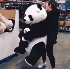 a woman is hugging a giant panda bear