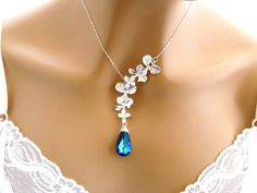 Romantic Jewelry Blue Crystal Necklace: Orchid Necklace, Flower Blue Swarovski Wedding Necklace, Peacock Bridal Necklace, Orchid Wedding Jewelry Wow, what an elegant and totally feminine necklace - Orchids and Bermuda Blue Swarovski crystal! It features a double cascade of silver orchids linked together to allow free movement. Hanging below is a long, graceful and precision faceted Swarovski crystal teardrop Bermuda Blue pendant. The chain closes with a sterling silver lobster clasp finished wit Wedding Crystal Necklace With Flower Design, Flower Crystal Wedding Necklace, Wedding Crystal Flower Necklace, Blue Flower-shaped Wedding Jewelry, Blue Crystal Bridal Necklace Gift, Blue Crystal Bridal Necklace For Gift, Blue Flower Necklace For Wedding, Elegant Blue Wedding Necklaces, Elegant Blue Wedding Necklace