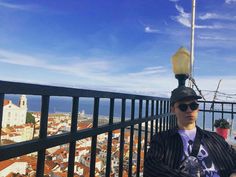 a man standing on top of a balcony next to a street light