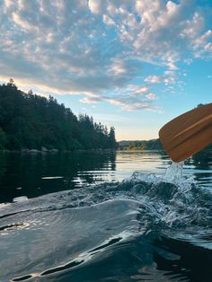 a person riding on top of a surfboard in the middle of water with trees in the background