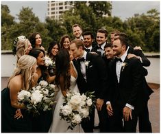 a group of people standing next to each other in front of trees and water with white flowers