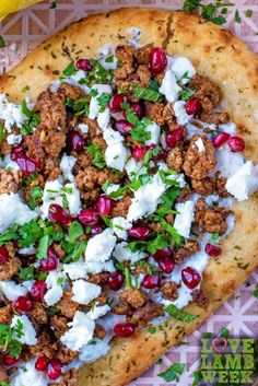 a pizza topped with meat, feta cheese and pomegranate on top