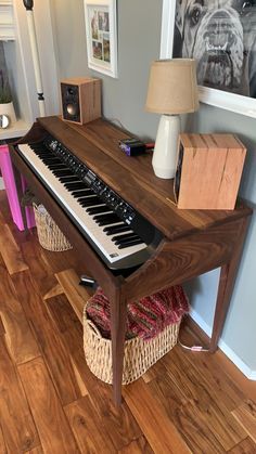 a piano sitting on top of a hard wood floor next to a lamp and pictures