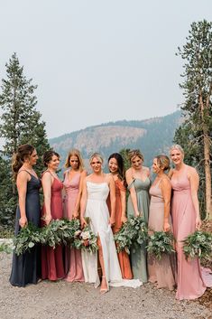 Seven bridesmaids in multicolored dresses stand around a bride in a modern dress against a mountain background. Eucalyptus Bouquets, August Wedding Colors, Mismatched Bridesmaids Dresses, Fall Mountain Wedding, Mix Match Bridesmaids, Fall Wedding Color Palette, Wedding Parties Colors, Events Planning