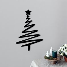 a christmas tree made out of black paper on a table next to flowers and candles