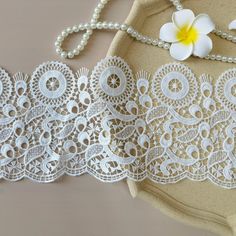 three pieces of white lace next to a flower