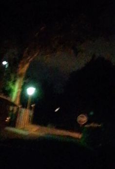 the street light is glowing green in the dark night time sky, and it appears to be blurry