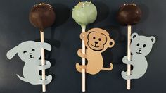 three cake pops with animals on them and one is holding a chocolate lollipop