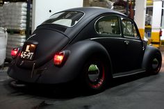 an old vw bug sits parked in a garage