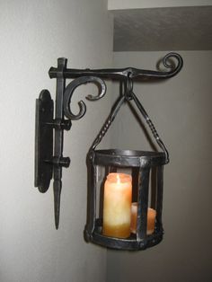 a candle hanging from a wall next to a light fixture with a candle in it