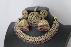 * Necklace Length - 14 -16 inches adjustable * Necklace Width - 1.2 Inch * Earrings Length - 1.7 inches * Earrings Width -0.4 inches **Simi Lavender Polki Choker Necklace** Elevate your elegance with the Simi Lavender Polki Choker Necklace, a masterpiece of Indian jewelry craftsmanship. This exquisite piece blends traditional charm with contemporary sophistication, making it a standout accessory for any occasion. **Design and Craftsmanship. - **Lavender Hues Adorned with delicate lavender-colored stones, this choker introduces a serene and graceful tone to your ensemble, perfectly complementing a variety of outfits. - **Intricate Setting Handcrafted with meticulous attention to detail, the necklace boasts an intricate setting that highlights the faux Polki and enhances their brilliance. ** Adjustable Pink Jeweled Jewelry, Purple Party Jewelry With Adjustable Chain, Traditional Adjustable Purple Jewelry, Purple Jeweled Jewelry For Wedding, Purple Wedding Jewelry With Jewels, Purple Costume Jewelry For Wedding, Adjustable Plated Round Necklace, Festive Dangle Jewelry With Adjustable Chain, Adjustable Plated Necklaces