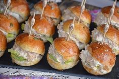 several mini sandwiches with toothpicks in them sitting on a black tray next to other food items