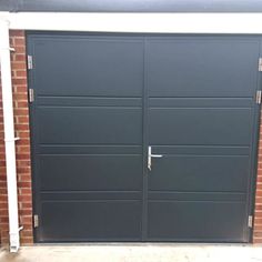 an image of a garage door that is painted dark grey and has brick pillars in the background