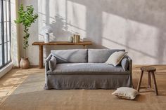 a living room with a gray couch and wooden table next to it on top of a carpeted floor