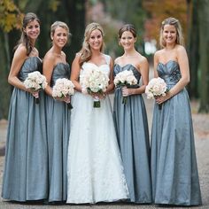 a group of women standing next to each other wearing dresses and holding bouquets in their hands