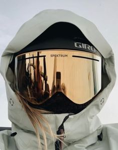 a person wearing ski goggles and a white jacket with hood up on their head