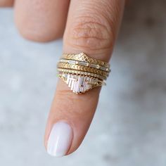 a woman's hand with three different rings on top of her finger and the other ring