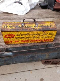 an old metal box with writing on it sitting on top of a wooden table next to other items