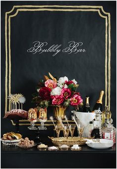 a table topped with lots of desserts and drinks next to a chalkboard sign