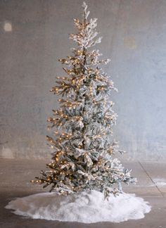 a small white christmas tree with snow on the ground