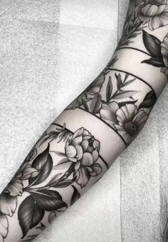 a woman's arm with flowers and leaves tattooed on the forearm, in black and white