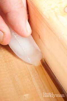 a person using a knife to cut something on a wooden surface with wood grain in the background