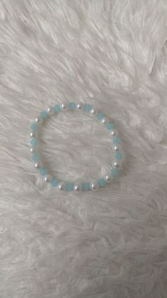 a bracelet with white pearls and blue beads on top of a furnishing area