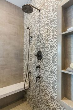 a bathroom with a shower head, shelves and tiled walls