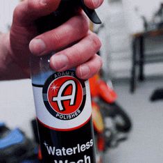 a person holding a waterless wash bottle in their hand with other tools behind them