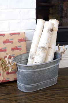 a metal bucket filled with logs sitting on top of a wooden table