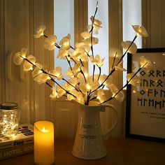 a vase filled with white flowers next to a lit candle and some books on a table