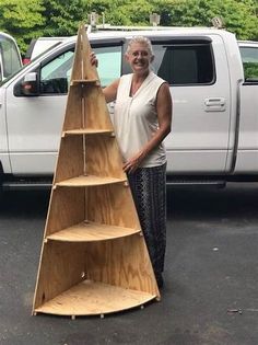 a woman standing next to a tall wooden shelf in front of a white pickup truck