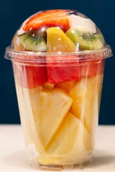 a plastic cup filled with fruit on top of a table